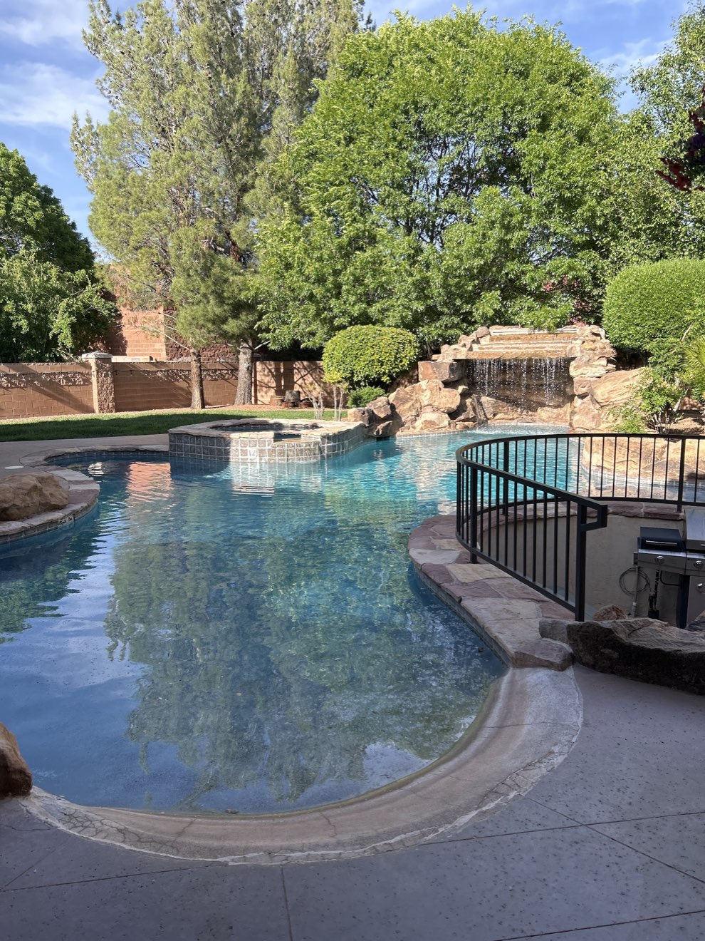 Resort-style pool with a rock waterfall and spa, kept clear by First Chance Pool Service
