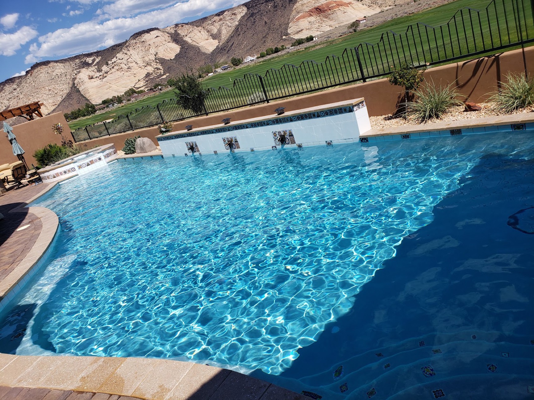 A bright turquoise pool kept by First Chance Pool Service, red-rock cliffs of St. George behind it