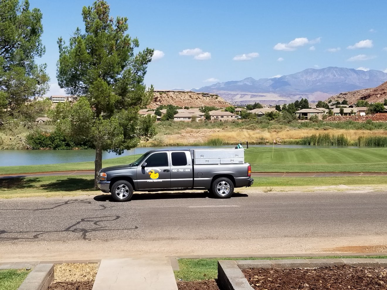 The First Chance Pool Service truck parked by a St. George pond, red-rock mountains behind it